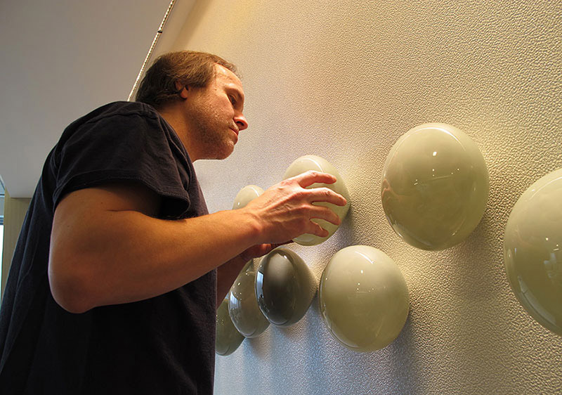 Glass wall sculpture installation Bernard Katz close-up installing grey form