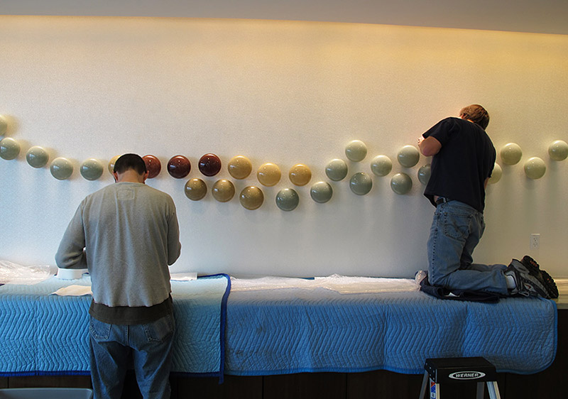Glass wall sculpture installation Bernard Katz and Chad Chaney installing second row